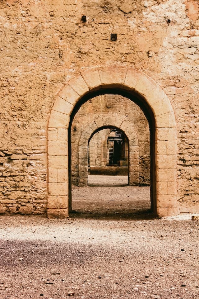 Vue d'une arche ouverte dans un ancien mur en pierre. Au travers de cette arche, on en voit une autre de la même forme, et ce récursivement.